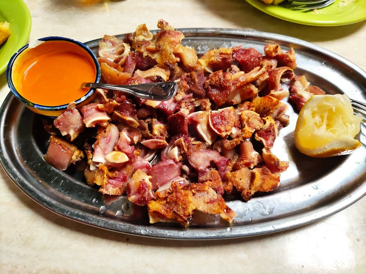Plato de carnitas crujientes con salsa roja y limón